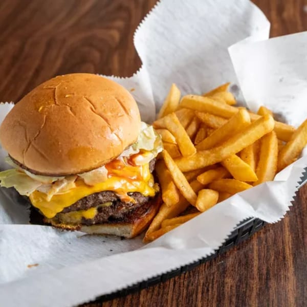 A double cheeseburger with melted cheese and lettuce, served with a side of golden fries.